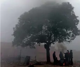  ?? — PTI ?? People sit around a fire to keep themselves warm during a foggy morning in New Delhi on Monday.