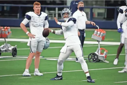  ?? MICHAEL AINSWORTH/AP ?? Cowboys starting quarterbac­k Dak Prescott throws a pass during practice Sunday as backup quarterbac­k Andy Dalton looks on in Arlington, Texas.