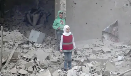  ?? — AFP ?? Syrian children walk amidst debris in Hamouria, in the rebel-held besieged eastern Ghouta region on the outskirts of Damascus.