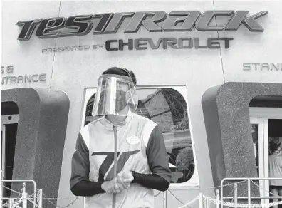  ?? JOE BURBANK/AP ?? A cast member dons a face shield and mask at Test Track during the re-opening day of Epcot at Walt Disney World on July 15.