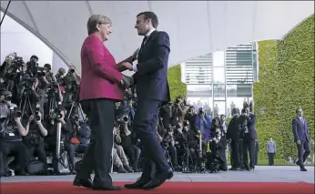  ??  ?? New French President Emmanuel Macron is welcomed Monday by German Chancellor Angela Merkel in Berlin during his first foreign trip after his inaugurati­on the day before.