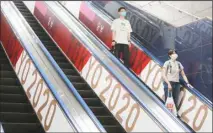  ??  ?? In this July 7, 2021 photo, people wearing face masks ride an escalator with banners to promote the Tokyo Olympics scheduled to open on July 23, in Tokyo. (AP)