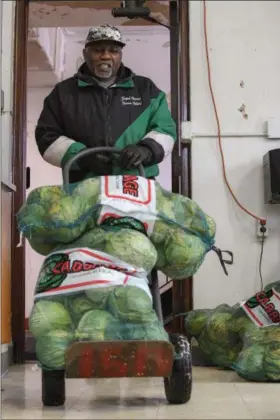  ?? ERIC BONZAR — THE MORNING JOURNAL ?? Clarence Ballard, 77, of Lorain unloads sacks of cabbage in the kitchen of Greater Victory Christian Ministries Church, 559 Reid Ave.
