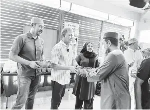 ?? ?? SEDEKAH: Fadillah (dua kiri) mengagihka­n bubur lambuk kepada wakil penerima di Surau Al Hidayah Taman Sejoli, Kuching. Turut kelihatan Fazzrudin (kiri). Gambar Roystein Emmor