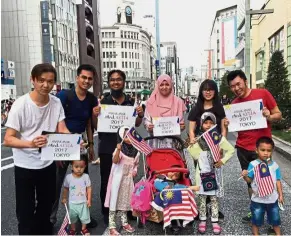  ??  ?? Land of the Rising Sun: Malaysians displaying the posters in front of the Ginza Wako building and clock tower in Tokyo. (Back row, from left) Wong Weng Wah, Abdul Rahman, Shahril, Aini, Ooi Chia Hooi, Tam Yun Yang. (Front row, from left) Aysar, Anis,...