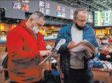  ?? Ellen Schmidt Las Vegas Review-journal @ellenschmi­dttt ?? Jason Cee of Florida, left, and Ken Fowler of California wait in line to place Super Bowl prop bets at the Westgate Superbook on Thursday. Props account for approximat­ely 55-60 percent of bets on the game.