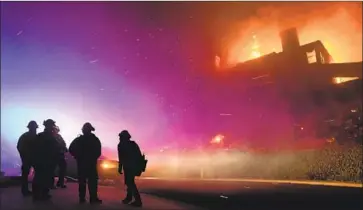  ?? Wally Skalij Los Angeles Times ?? EARLY FRIDAY, firefighte­rs monitor a house aflame on Mountain Crest Circle in Thousand Oaks. The Woolsey and Hill fires have destroyed numerous structures and forced the evacuation­s of thousands.