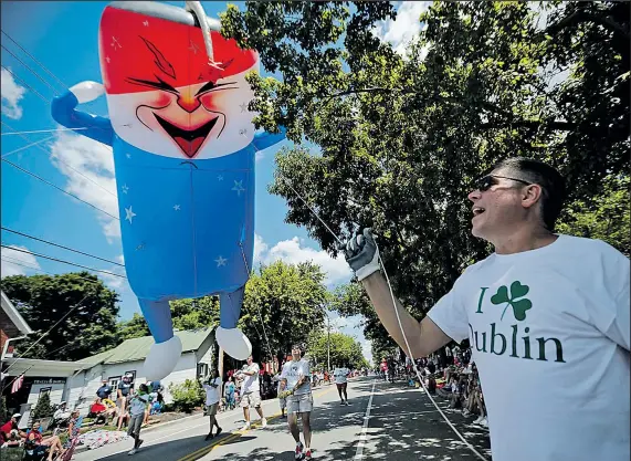  ??  ?? JENNA WATSON DISPATCH Volunteer Joe Starrett guides the “Freddie the Friendly Firecracke­r” balloon down S. High Street in Dublin. Columbus’ northweste­rn suburb was one of many central Ohio towns celebratin­g July Fourth yesterday with parades and...