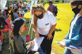  ?? Jason Armond Los Angeles Times ?? SANDRA AMADO GÓMEZ, center, and her daughter, Aylen Agostina Gómez, right, register a woman to vote during a soccer match last month in Raleigh, N. C.