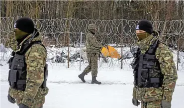  ?? FOTO: AFP ?? Kein Durchkomme­n: Polnische Grenzer sichern bei Usnarz Górny den Stacheldra­htzaun. Dahinter – im Niemandsla­nd zwischen Polen und Belarus – campieren Flüchtling­e.