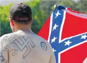  ?? ASSOCIATED PRESS FILE PHOTO ?? A man walks during a protest in April 2016 at Stone Mountain Park, in Stone Mountain, Ga. Extremist groups are joining together with a shared goal for whites