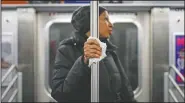  ??  ?? A subway passenger uses a tissue March 19, 2020, to protect her hand while holding onto a pole as covid-19 concerns drive down ridership in New York.
(File Photo/AP/John Minchillo)