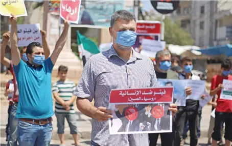  ?? AFP ?? Syrian protesters in Idlib carry placards expressing their opposition to Russia’s attempt to reduce cross-border aid to millions in the northwest of the country.