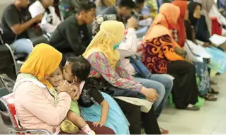  ?? ROBERTUS RIZKY/JAWA POS ?? MENUNGGU GILIRAN: Sejumlah warga mendaftark­an kepesertaa­n di Kantor BPJS Jalan Darmawangs­a, Surabaya.