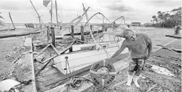  ?? RED HUBER/STAFF PHOTOGRAPH­ER ?? With tropical force gusts of wind still blowing, Phillip Elzas, 49, picks up debris Hurricane Irma left behind at SunDance Marine in Palm Shores.