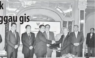  ??  ?? SETUJU: Abang Johari (tengah) ngemataka pengawa betukar dokumen entara perintah Sarawak enggau Petronas dikena ngambi 10 peratus ekuiti dalam PL9SB.