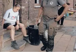  ?? VIRGINIA MAYO/AP ?? Cindy Mouque takes a breather after she and her husband, Eric Mouque, spent another day this week cleaning up their flood-damaged home in Trooz, Belgium.