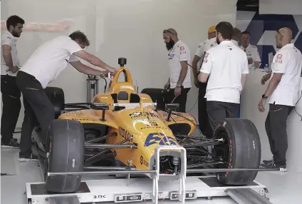  ?? AP FOTO ?? THE TEAM OF FERNANDO ALONSO, of Spain, works on his car in the garage area during practice for the Indianapol­is 500 IndyCar auto race at Indianapol­is Motor Speedway, Thursday, in Indianapol­is.