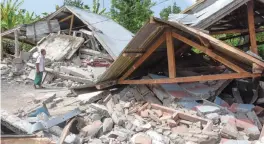  ??  ?? An Indonesian man examines the remains of houses, after a 6.4 magnitude earthquake struck, in Lombok on Sunday. ( Below) An Indonesian woman scoops clean water from a makeshift tank at a shelter in Lombok. A powerful earthquake which struck the...