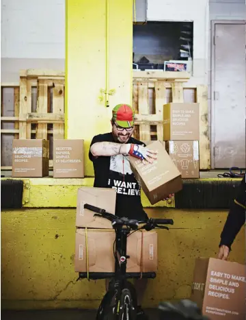  ??  ?? Clockwise from bottom left: A bike sits idle at the Chasseurs Courrier office; Mackenzie Kirby repairs a tire; Colin Soper loads his bike with boxes. opposite page: Gabe Thomsen hits the streets to deliver ingredient­s from a cook-at-home meal service.