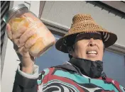  ?? DARRYL DYCK / THE CANADIAN PRESS ?? Christine Smith-Martin, of the Tsimshian First Nation, holds a jar of salmon before the government announced the approval of the Pacific NorthWest LNG project.