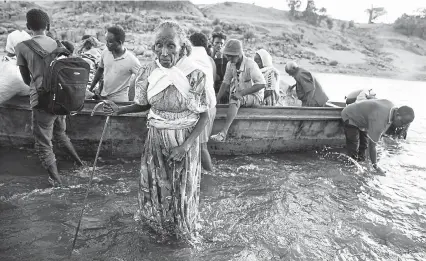  ?? Tyler Hicks, © The New York Times Co. ?? Refugees return to the river they crossed to get into Sudan from Ethiopia to gather water and bathe, in Hamdayet, Sudan, on Dec. 5. Tens of thousands of Christian refugees, fleeing the violence in the Tigray region of Ethiopia, have been given a warm welcome by the residents of the Sudanese town.