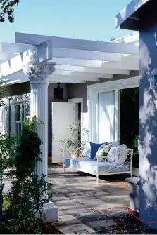  ??  ?? The home’s facade is modern and inviting thanks to the light grey with its warm brown undertone. The original pergola was painted white and pillars were added for contrast. Exterior walls painted with Plascon Beijing Moon; daybed from MRP Home;...