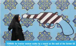  ??  ?? TEHRAN: An Iranian woman walks by a mural on the wall of the former US embassy in the Iranian capital yesterday. — AFP