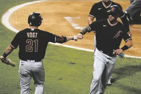  ?? ASSOCIATED PRESS ?? ARIZONA DIAMONDBAC­KS’ DAVID PERALTA (right) bumps fists with Stephen Vogt after Peralta scored on a single from Nick Ahmed during the second inning of a game against the Los Angeles Angels on Wednesday in Anaheim, Calif.