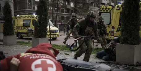  ?? Ap ?? SEEKING COVER: Ukrainian servicemen run for cover as explosions are heard during a Russian attack in downtown Kharkiv, Ukraine, Sunday.