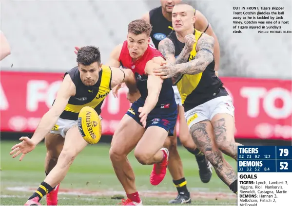  ?? Picture: MICHAEL KLEIN ?? OUT IN FRONT: Tigers skipper Trent Cotchin paddles the ball away as he is tackled by Jack Viney. Cotchin was one of a host of Tigers injured in Sunday’s clash.