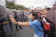  ?? FERNANDO LLANO/ASSOCIATED PRESS ?? University students confront a line of Venezuelan National Guard officers in riot gear during a protest outside of the Supreme Court in Caracas, Venezuela, Friday.