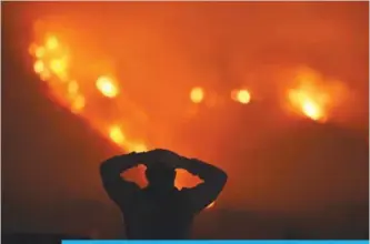  ?? —AFP ?? CALIFORNIA: A man watches the Thomas Fire in the hills above Carpinteri­a, California.