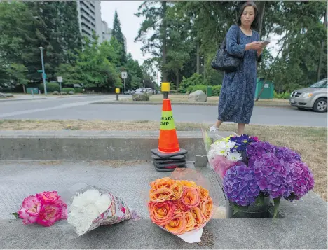  ?? JASON PAYNE ?? Family friend Emma Liu looks at flowers that mark a memorial for Marrisa Shen on the east side of Central Park in Burnaby on Friday. The 13-year-old was found dead in the park early Wednesday morning after being reported missing.