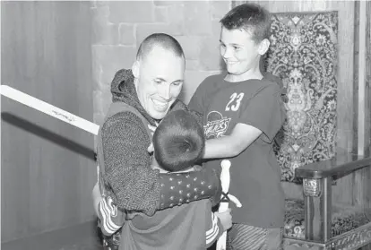  ?? PAUL W. GILLESPIE/BALTIMORE SUN MEDIA GROUP ?? Marine Maj. Chris Paes hugs his children, Jacob, 6, back to camera, and Elijah, 9. Paes dressed as a knight at Medieval Times in Hanover to surprise the boys on his return from a seven-month deployment in Iraq.