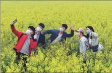  ?? LI JIANAN / XINHUA ?? Tourists take selfies in a field in Baofeng county, Henan province, in March.