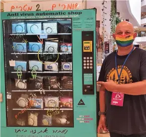  ?? (Tal Yisraeli) ?? ALEX KAPLAN of Tel Aviv’s Dizengoff Center shows off a vending machine selling the mall’s special pride coronaviru­s masks in rainbow colors.