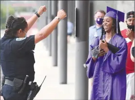  ?? (NWA Democrat-Gazette/J.T. Wampler) ?? Graduate Chloe Augustine-Jefferson smiles as Fayettevil­le police officer Julia McKinney cheers her graduation Thursday after a social distancing ceremony at Fayettevil­le High School for the Class of 2020. This ceremony was for FHS, Fayettevil­le Virtual Academy and ALLPS grads. Graduates were allowed two guests to walk with them through the school to receive their diplomas in a nearly empty auditorium. McKinney is a school resource officer at the high school. Visit nwaonline. com/200702Dail­y/ for photo galleries.