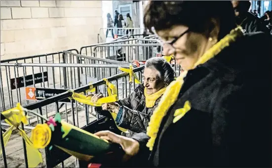  ?? LLIBERT TEIXIDÓ ?? Una mujer anuda una cinta amarilla en las vallas que rodean el Palau de la Generalita­t, anoche, en la plaza Sant Jaume