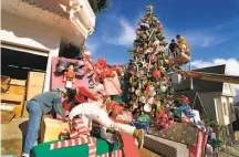  ?? Liz Hafalia / The Chronicle 1997 ?? In 1997, Tom Taylor ( bending over in white) was busy constructi­ng the holiday display at his Castro neighborho­od home, and the Norfolk Island pine was much shorter.