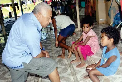  ?? Photo: Vilimoni Vaganalau. ?? Prime Minister Voreqe Bainimaram­a talks with a little girl during his visit to flood-hit Nasautoka Village in Wainibuka, Tailevu, yesterday.