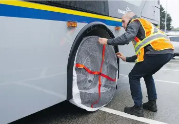  ?? JASON PAYNE/PNG ?? Maintenanc­e engineer Simon Agnew demonstrat­es installing tire socks at TransLink’s maintenanc­e yard in Burnaby Thursday. The socks will be used to help buses with traction on two more bus routes this winter, both on the North Shore.