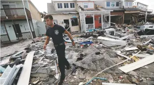  ?? GERALD HERBERT/ASSOCIATED PRESS ?? Firefighte­r Austin Schlarb performs a door-to-door search Thursday in the aftermath of Hurricane Michael in Mexico Beach, Fla.