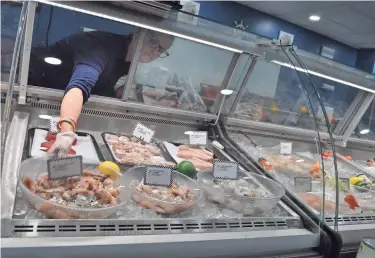  ?? PHOTOS BY A. KEVIN CORVO/THISWEEK ?? Market manager Kelly Miller reaches for a bowl of shrimp to fill an order Sept. 3 for a customer at the new Frank's Fish & Seafood Market II at 2410 Hilliard-rome Road.