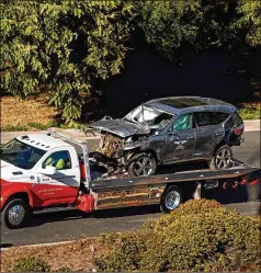  ?? LOS ANGELES TIMES ?? A tow truck hauls away the SUV driven by Tiger Woods when he ran off the road and sustained major injuries Tuesday in Los Angeles. Doctors inserted a rod into Woods’ right tibia and pins and screws into his ankle.