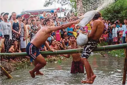  ?? AFP PIC ?? Youth playing a pillow fight game on a bamboo pole during festivitie­s marking Myanmar’s 70th Independen­ce Day, on the outskirts of Yangon yesterday.