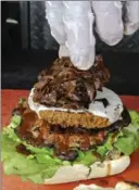  ??  ?? Caramelize­d onions are placed on a Le Bleu burger with blue cheese that sits on top of portobello mushroom and lettuce.