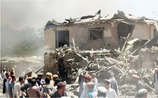  ?? (AP PHOTO) ?? SUICIDE BOMBING. Civilians and Afghan security forces walk at the site of a suicide attack in the Urgun area of Paktika, Afghanista­n. The attack near a busy market and a mosque killed at least 89 people in the deadliest insurgent attack on civilians...