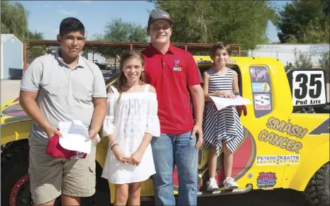  ??  ?? FROM LEFT: Meadows Union School District seventh grade students Elliot Ortiz and Bella Fusi, off-road racer Cole Mamer and Meadows Union fourth grade student Giada Fusi pose for a photo behind Mamer’s Pro-lite truck wrapped in Elliot’s winning design....