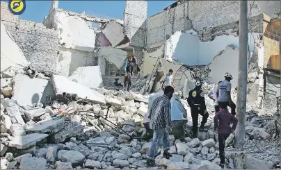  ?? CP PHOTO ?? In this photo provided by the Syrian Civil Defense group known as the White Helmets, members of the Civil Defense group and residents inspect damaged buildings after airstrikes hit the Bustan al-Qasr neighborho­od in Aleppo, Syria, Sunday.